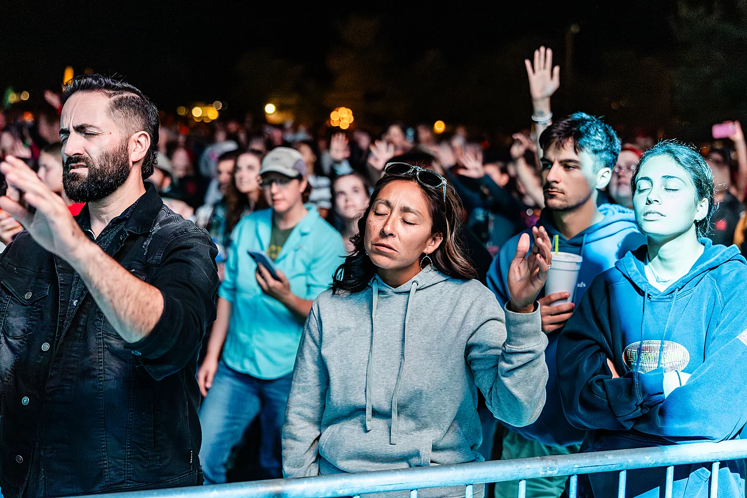 A man worships with hands raised in the crowd